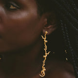 Close-up of a person wearing gold earrings with a dark background