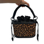 Leopard print handbag with black handle and strap on a white background.