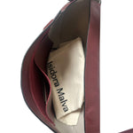 Close-up of a red handbag with 'Isidora Malva' branding on a white background.