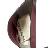 Close-up of a red handbag with 'Isidora Malva' branding on a white background.