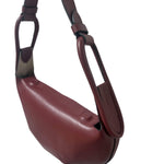 Maroon handbag with a strap on a white background.