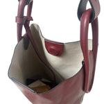 Brown leather handbag with beige interior on a white background.
