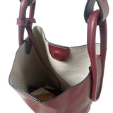 Brown leather handbag with beige interior on a white background.