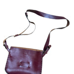 Red leather crossbody bag on a white background.