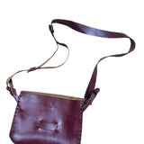 Red leather crossbody bag on a white background.