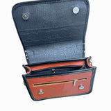 Brown and black leather crossbody carriel bag with decorative elements on a white background.