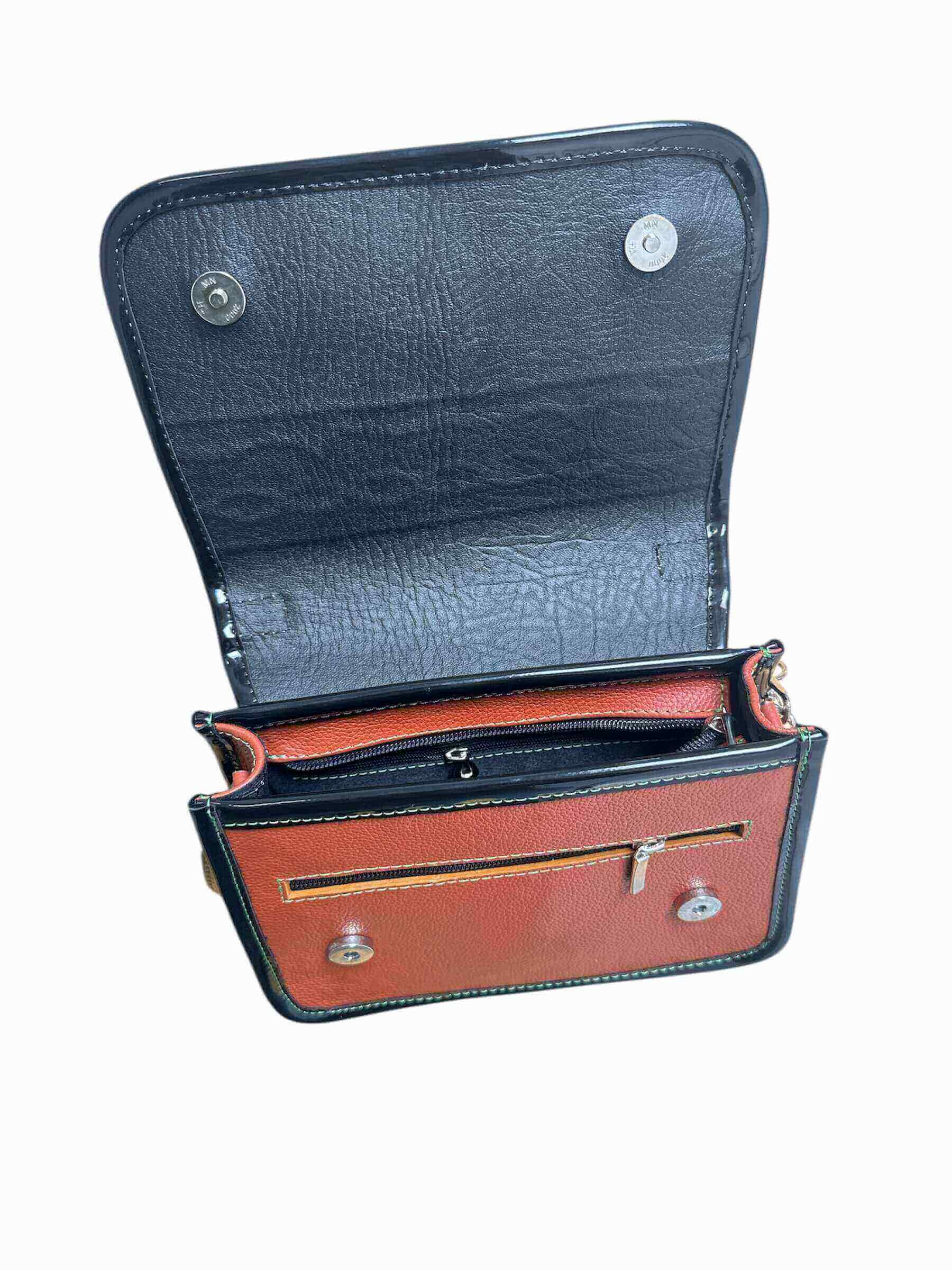 Brown and black leather crossbody carriel bag with decorative elements on a white background.