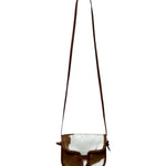 Brown and white cowhide crossbody bag on a white background