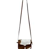 Brown and white cowhide crossbody bag on a white background