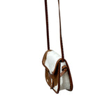Brown and white cowhide crossbody bag on a white background.