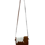 Brown and white cowhide crossbody bag on a white background.