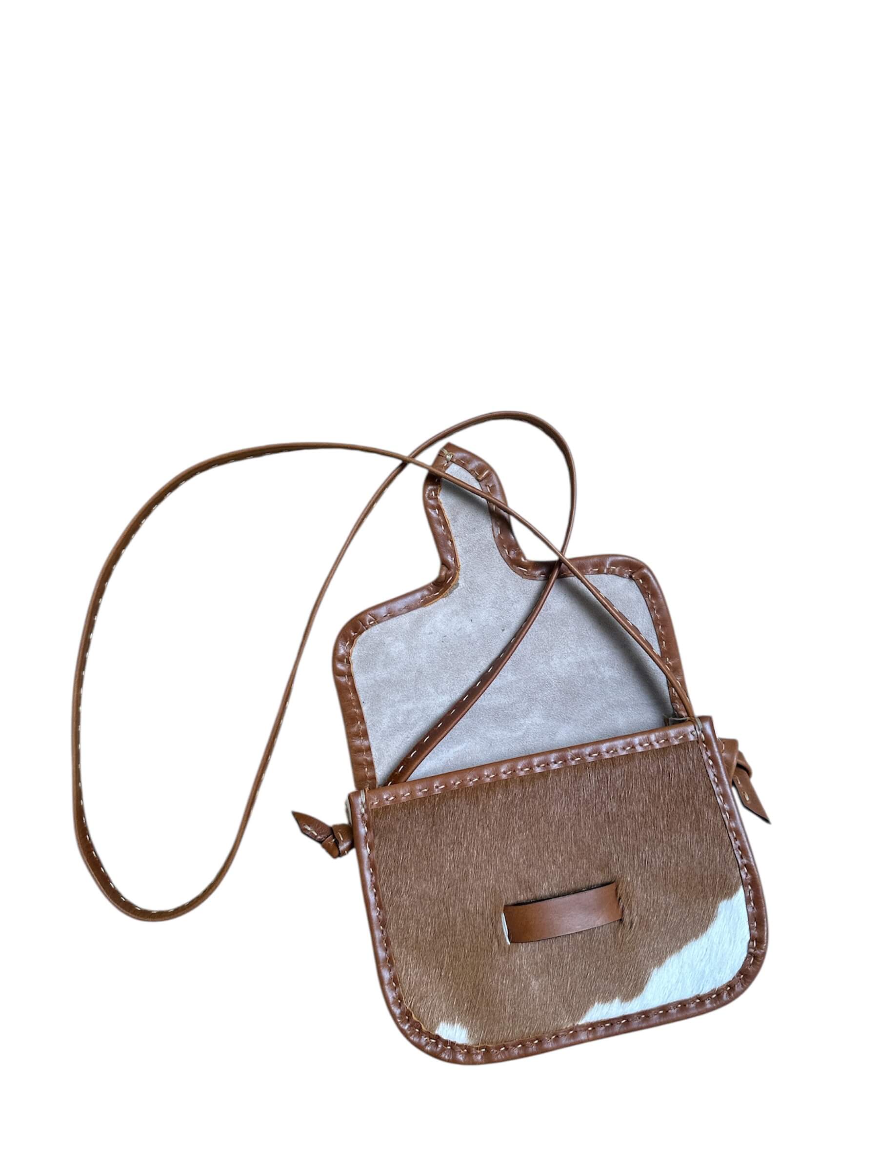 Brown and white cowhide crossbody bag on a white background.