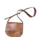 Close-up of a brown leather bag with visible stitching on a white background.