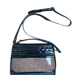 Black carriel crossbody purse with a strap and cow hide material on a white background.