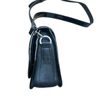 Brown and black leather crossbody carriel bag with decorative elements on a white background.