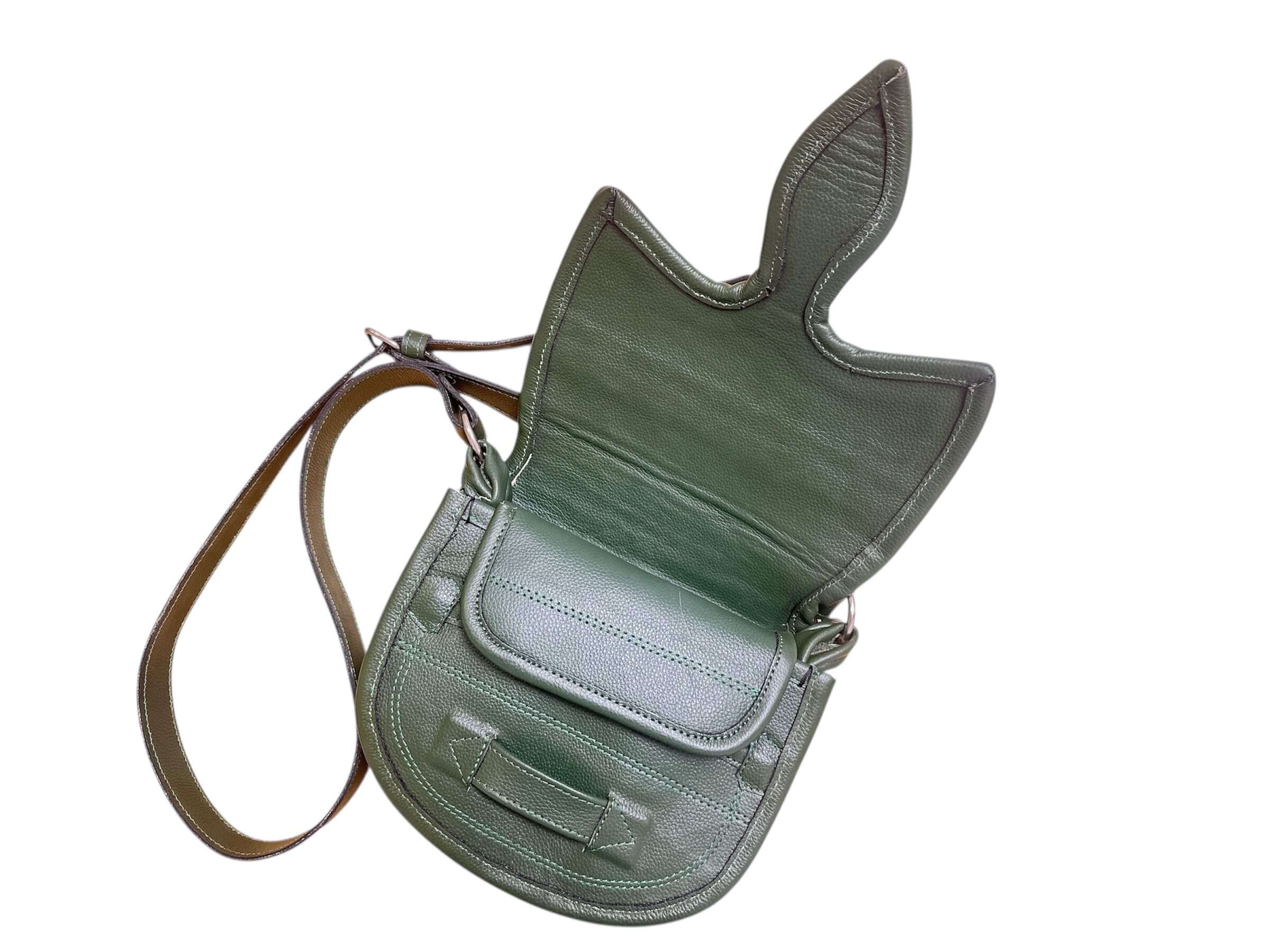 Green leather saddle bag with a strap on a white background. 