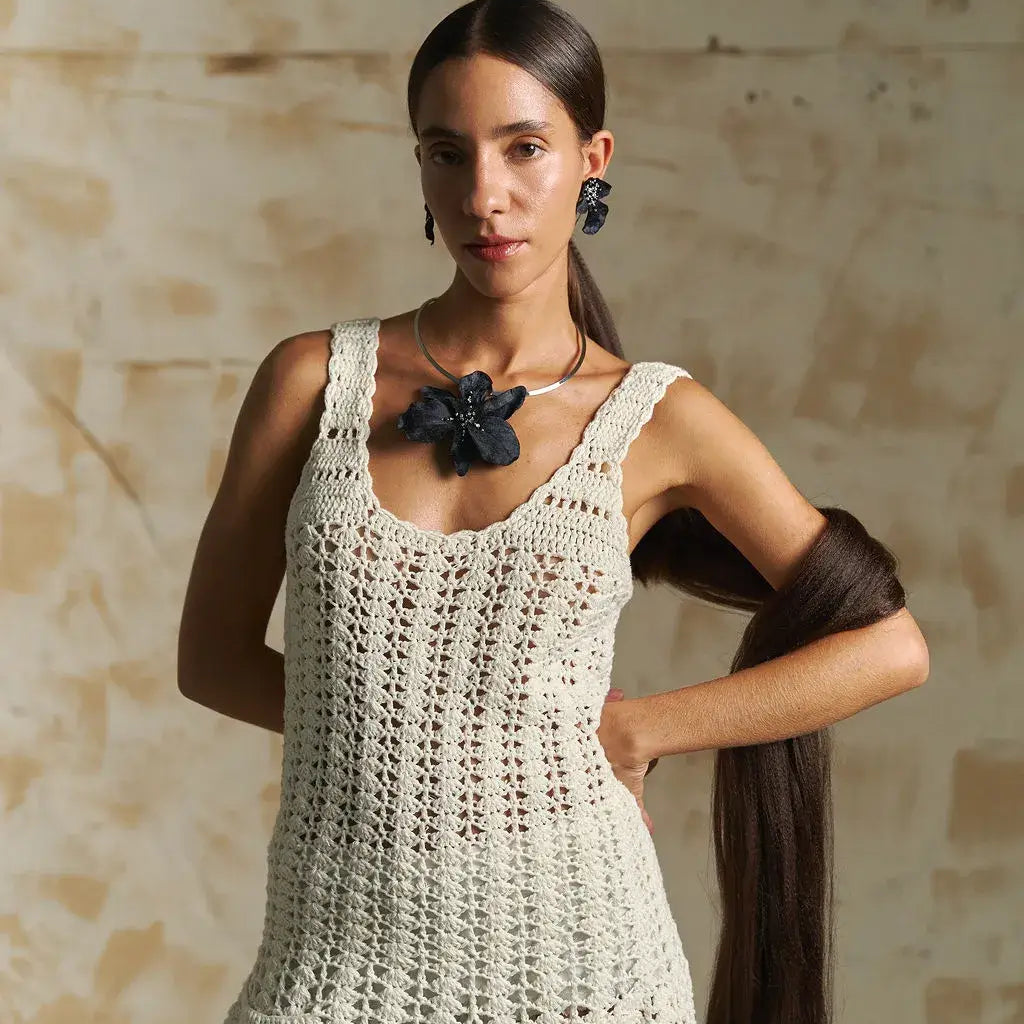 Woman wearing a white crochet dress with a neutral background