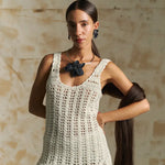 Woman wearing a white crochet dress with a neutral background