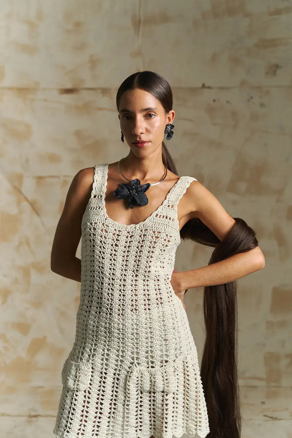 Woman wearing a white crochet dress with a neutral background