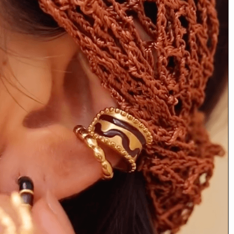 A close-up image of a woman's ear wearing a gold-plated ear cuffs.