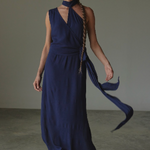 Woman wearing a long blue dress with a plain background