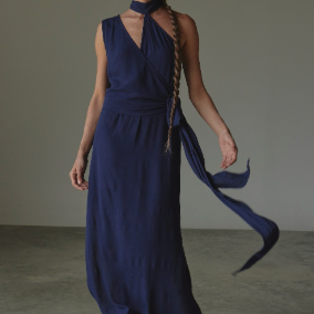 Woman wearing a long blue dress with a plain background