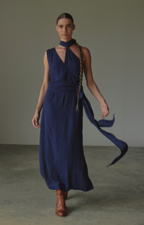 Woman wearing a long blue dress with a plain background