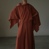 Woman wearing a terracota dress against a plain background.