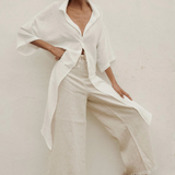 Woman wearing a white outfit with a plain background.