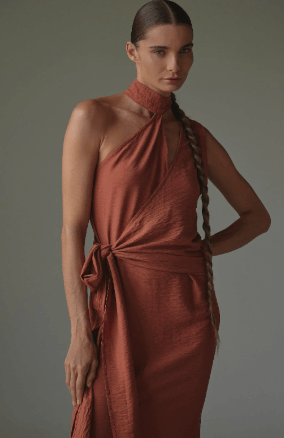 Woman wearing a rust-colored dress against a gray background.