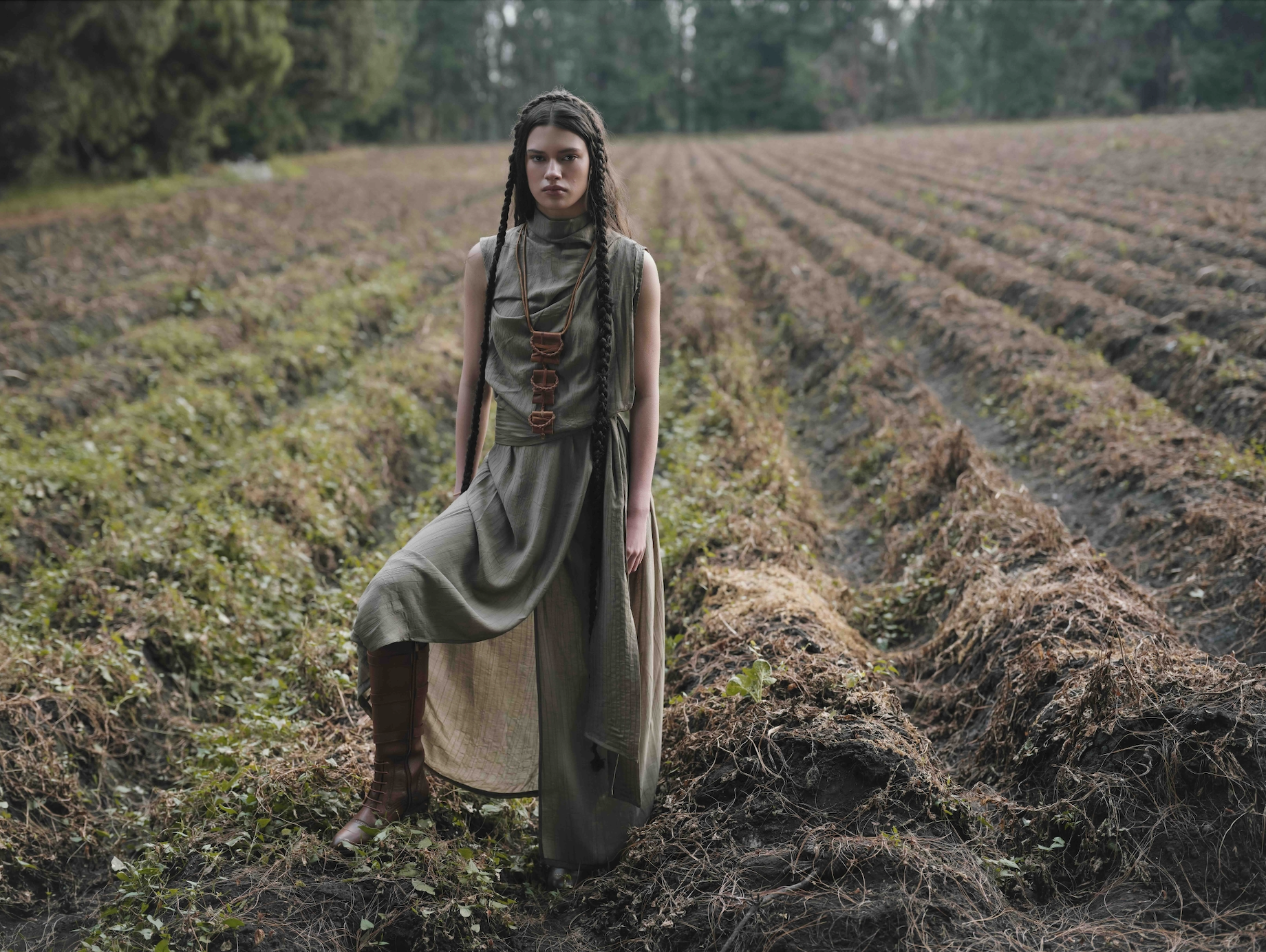 Woman in a long, flowing dress standing in a field with trees in the background