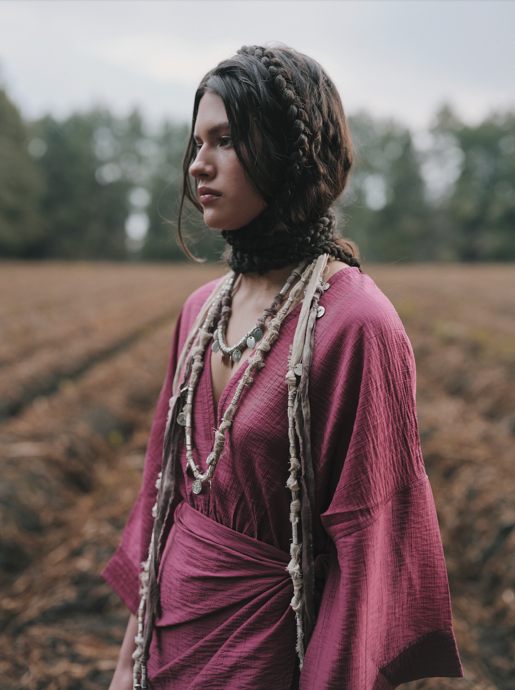 Woman in a purple dress with braided hair standing in a field