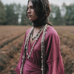 Woman in a purple dress with braided hair standing in a field