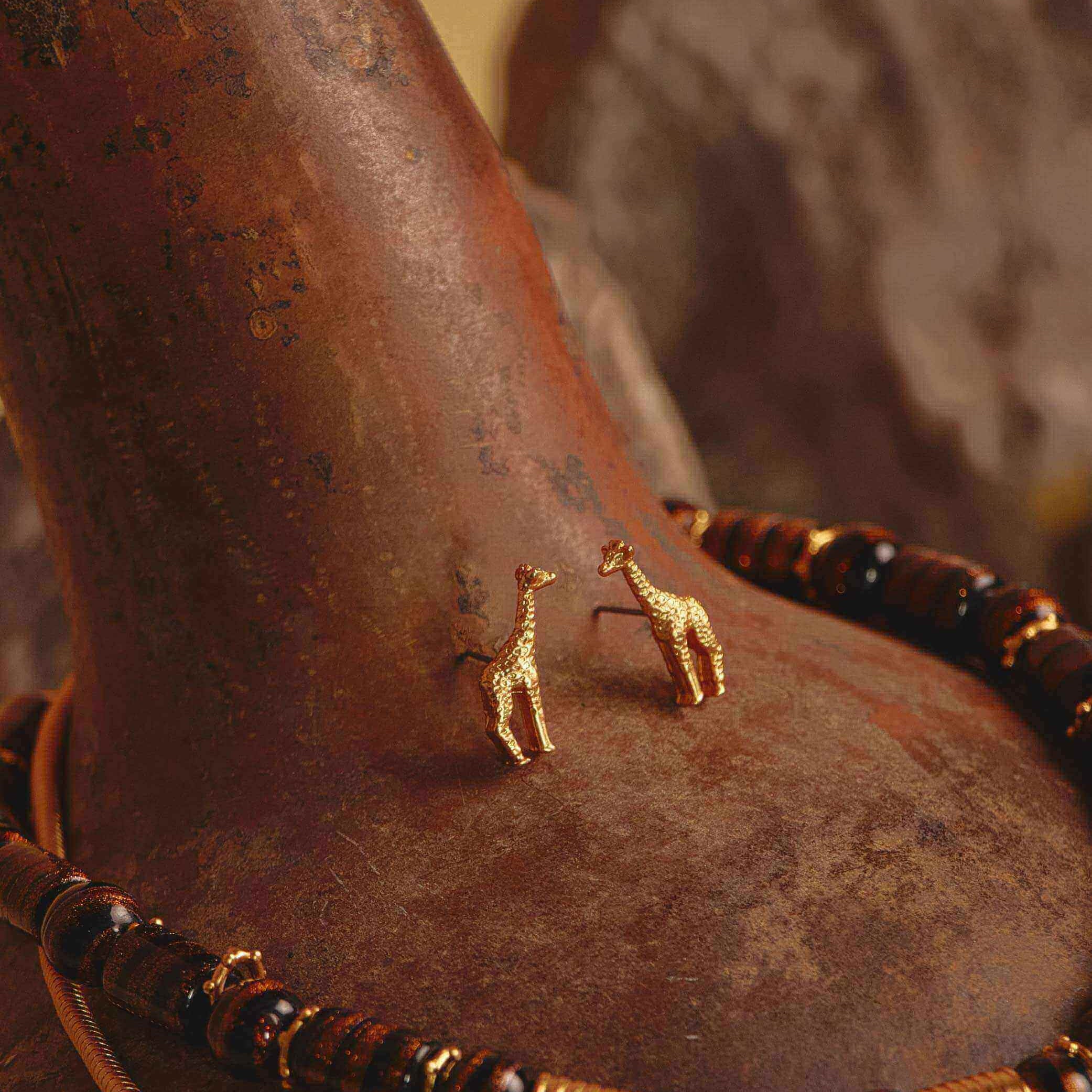 A gold-plated giraffe earring set with a beaded and gold accented necklace. 
