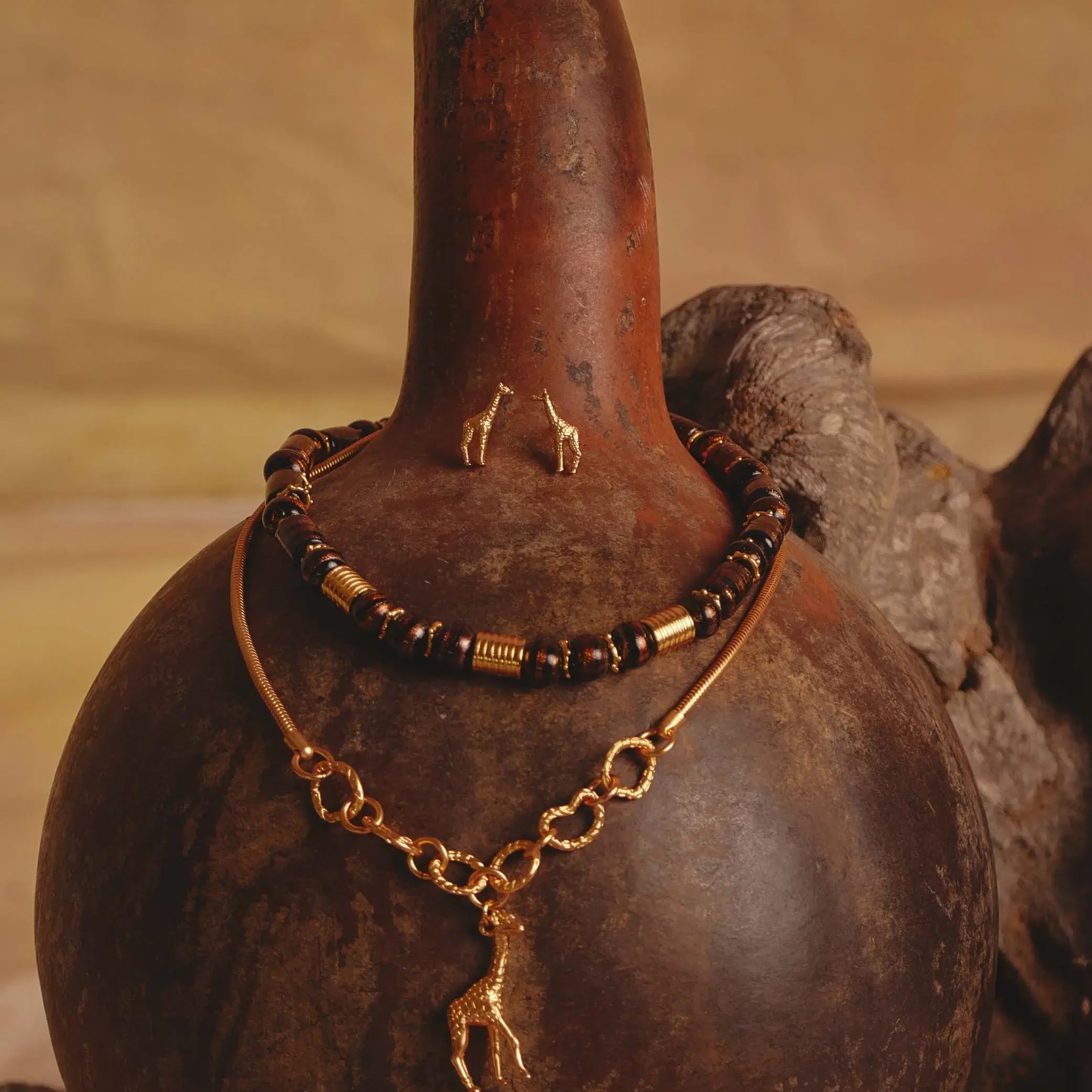 A gold-plated giraffe earring and necklace  set with a beaded and gold accented necklace as well as a giraffe pendant necklace. 