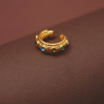 Gold hoop earring with gemstones on a brown background
