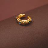 Gold hoop earring with gemstones on a brown background