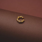 Gold hoop earring on a brown surface
