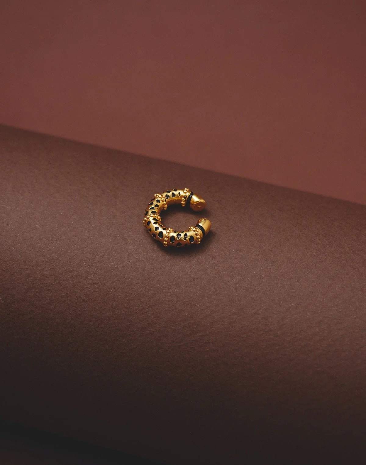 Gold hoop earring on a brown surface