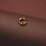 Gold hoop earring on a brown surface