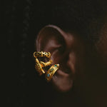 Gold earring with green gemstones on a dark background