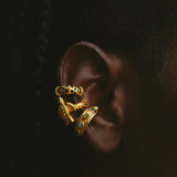 Gold earring with green gemstones on a dark background
