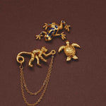 Gold animal-themed pins with a chain on a brown background