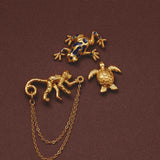 Gold animal-themed pins with a chain on a brown background