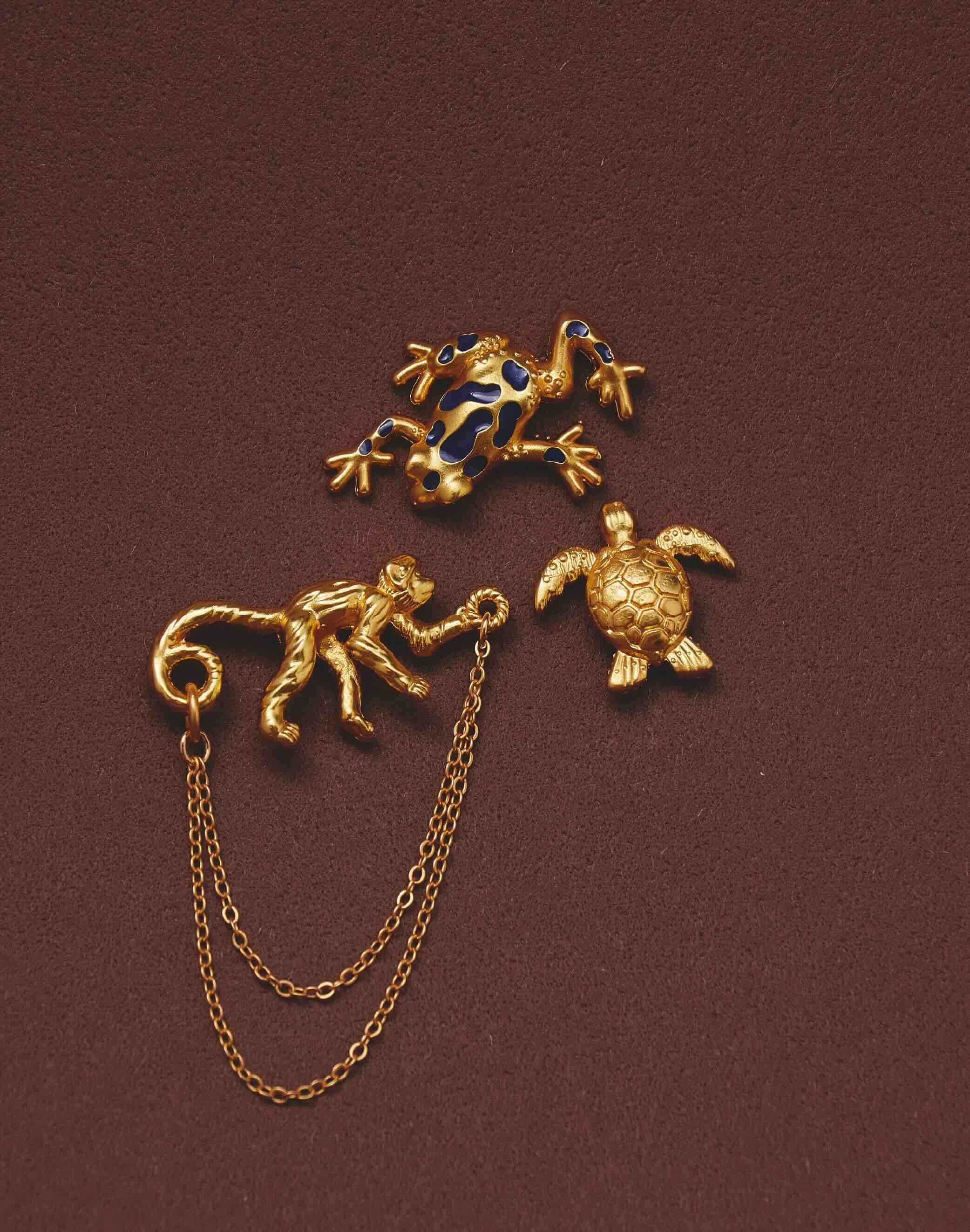 Gold animal-themed pins with a chain on a brown background
