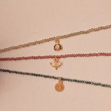 Three delicate necklaces with small charms on a beige background
