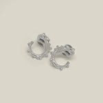 Pair of small sterling silver hoop earrings with bead detail on a neutral background