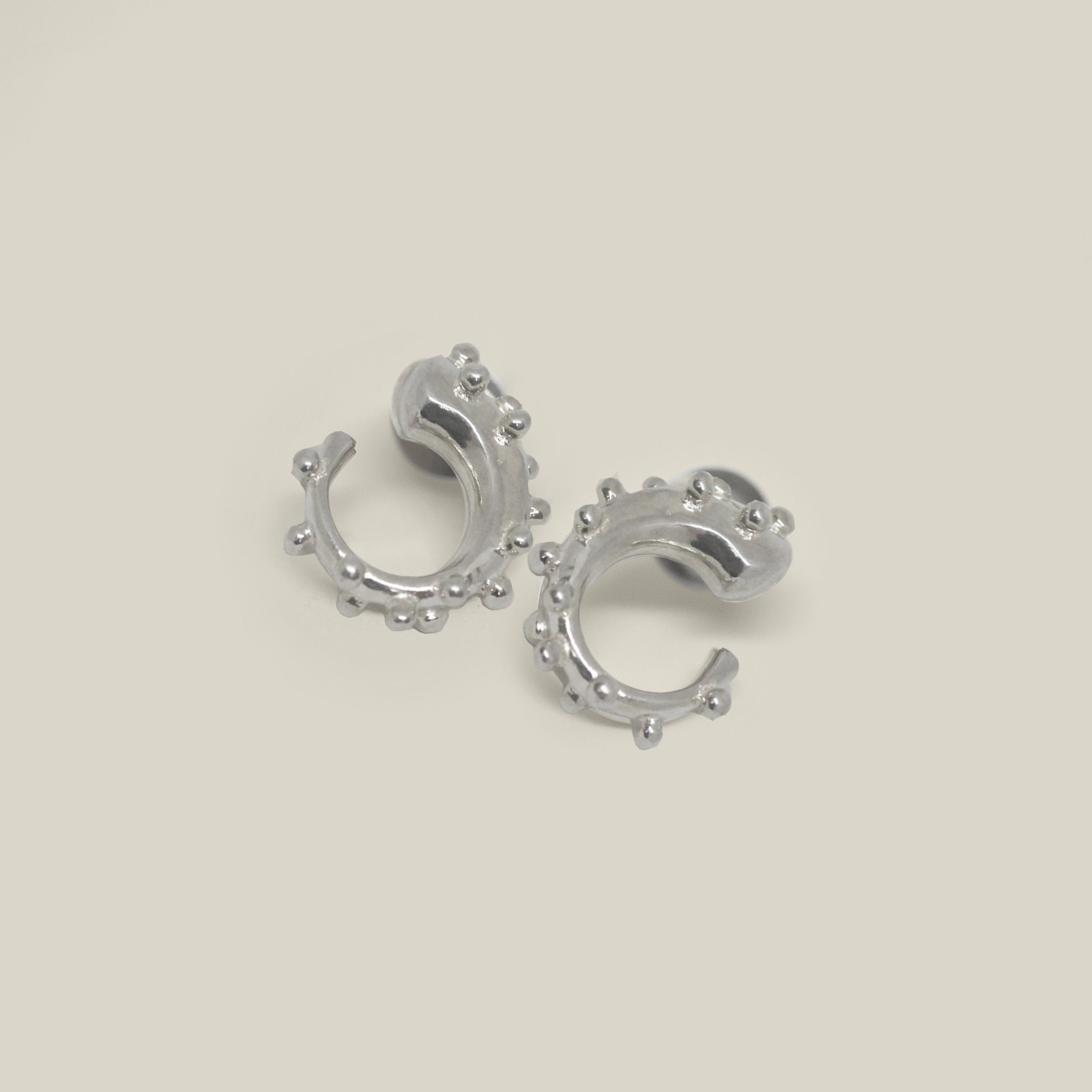 Pair of small sterling silver hoop earrings with bead detail on a neutral background