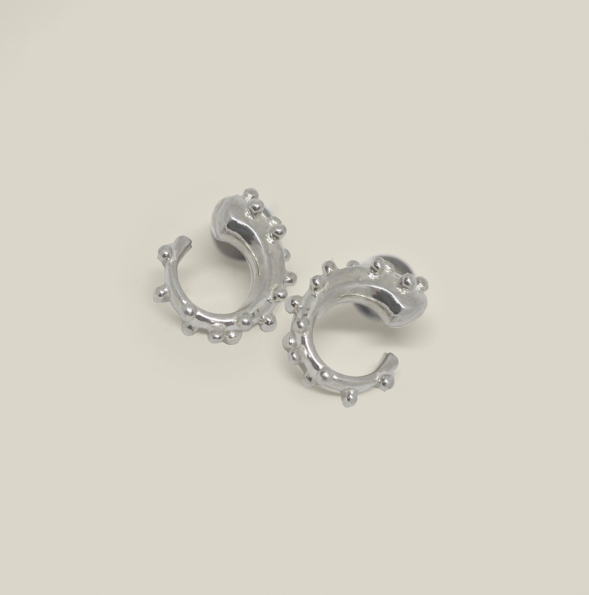 Pair of small sterling silver hoop earrings with bead detail on a neutral background