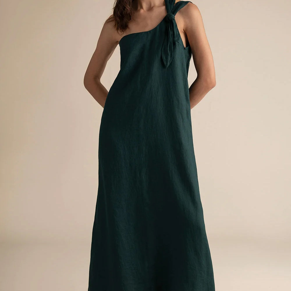 Woman wearing a dark green one-shoulder dress against a beige background.